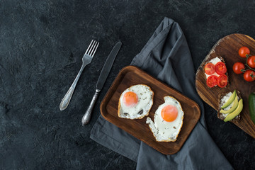 top view of fried eggs and healthy snacks for breakfast on dark tabletop