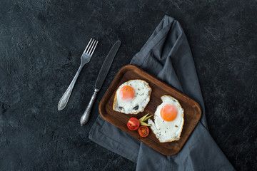 top view of fried eggs with cherry tomatoes slices for breakfast on dark tabletop