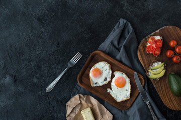 top view of fried eggs and healthy snacks for breakfast on dark tabletop