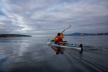 Adventurous woman is kayaking on a sea kayak during a vibrant morning. Taken in Vancouver, British Columbia, Canada.