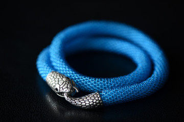 Blue beaded necklace with snake head lock on a dark background close up