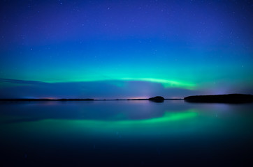 Fototapeta na wymiar Northern lightd dancing over calm lake in Farnebofjarden national park in Sweden.