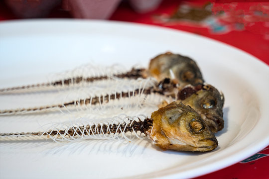 Skeleton of fish on a plate. On the plate are three fish heads and skeletons. Selective focus