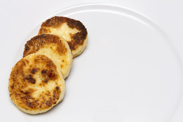 row of cheese pancakes on the white plate. Copy space