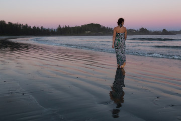 Woman Walking on a Sandy Beach during a vibrant and colorful summer sunset. Taken in Tofino, Vancouver Island, BC, Canada. © edb3_16