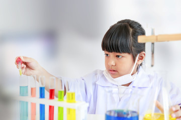 Asian girl doing laboratory test with colorful tubes, science classroom