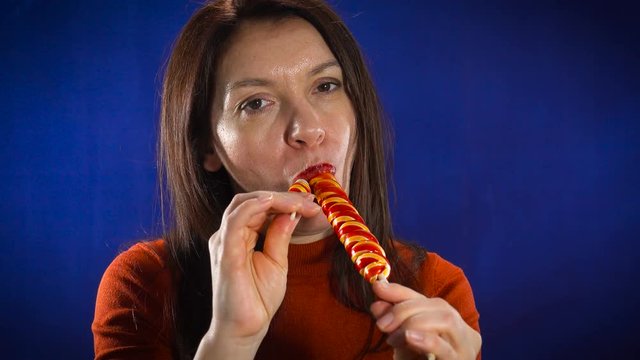 A beautiful brunette sensually eats candy.