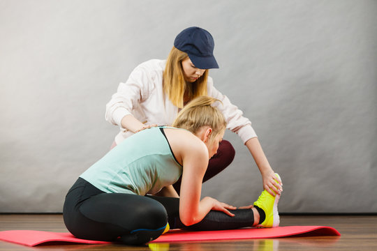Woman in sportswear stretching legs with trainer