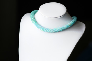 Seed bead necklace aquamarine color on a dark background close up