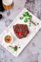 Top view grilled beef steak with beer, rosemary, herbs and spices on gray concrete background. restaurant kitchen concept