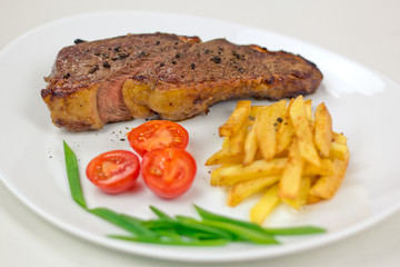 Fried steak with fries on a white plate