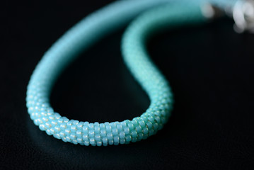 Seed bead necklace aquamarine color on a dark background close up