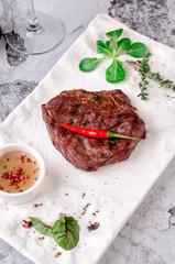 Top view close up, grilled beef steak with rosemary, herbs and spices on gray concrete background. and glass of red wine on table, restaurant kitchen concept
