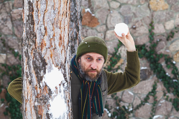 man with beard in his waistcoat throws snowballs between trees