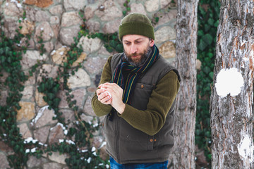 man with beard in his waistcoat throws snowballs between trees