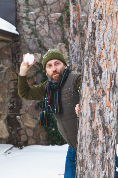 man with beard in his waistcoat throws snowballs between trees