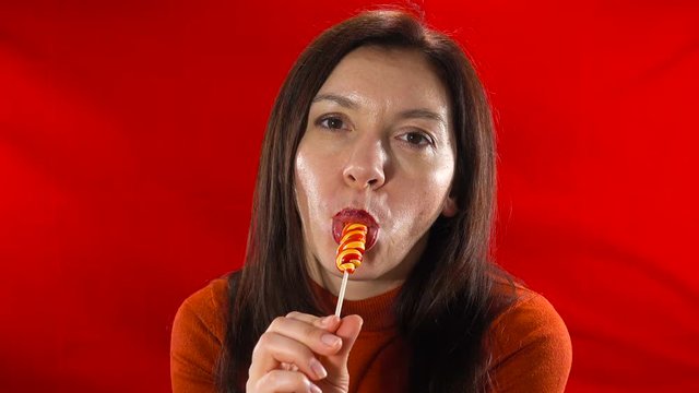 A beautiful, sensual brunette erotically sucks two candies.