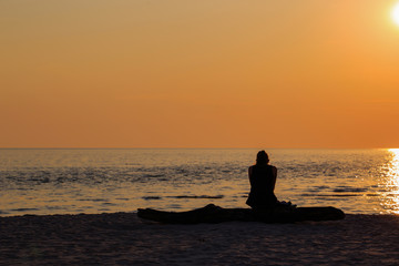 Naklejka na ściany i meble Woman sitting alone on the beach Silhouette style