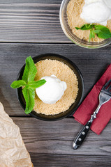 Top view close up Apple crumble dessert with vanilla ice cream, green mint on grey wooden table. fork with cake on paper