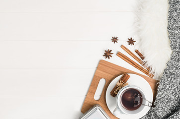 Mug with tea and home decor on white, cosy wooden table background. Winter morning relax concept, top view. Frame with cup and copy space around objects.
