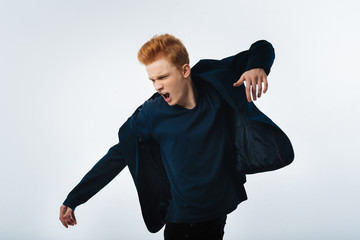 Dreamboat. Attractive determined red-haired young man wearing a jacket and shouting and moving