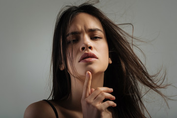 Thoughts. Beautiful meditative dark-haired young woman thinking and staring and touching her chin