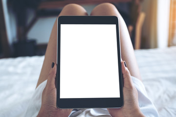 Mockup image of woman's hands holding black tablet pc with blank desktop white screen while lying...