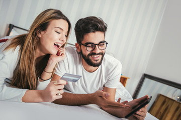 Couple Lying In Bed Using Tablet Computer Hold Credit card Online Shopping Payment,