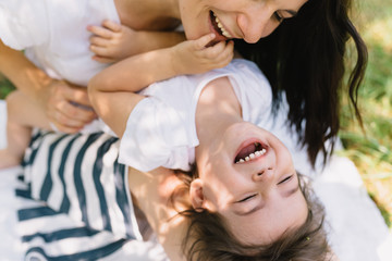 Cropped shot cute happy kid daughter and her beautiful mother playing outdoor. Cute mom and her child playing in the park together. Close-up portrait of happy family. Happy Mother's Day. Motherhood.