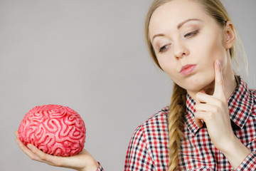 Woman thinking and holding fake brain