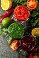 Indian traditional food, Set of three chutney for Chaat and Sev Puri - sweet date-tamarind, cilantro-mint green and red chilli garlic, On dark stone background, copy space top view