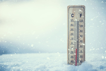 Thermometer on snow shows low temperatures under zero. Low temperatures in degrees Celsius and...