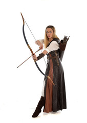 full length portrait of girl wearing brown  fantasy costume, holding a bow and arrow, on white studio background. 