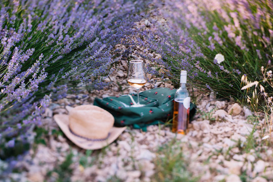 Fototapeta Picnic outdoors in lavender fields in Provence, south France. Rose wine in a glass, whole bottle of wine and a travel backpack