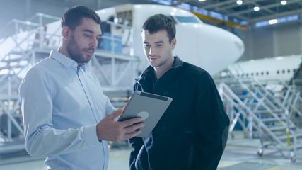 Aircraft Maintenance Worker and Engineer having Conversation. Holding Tablet. Shot on 4K UHD Camera. - Powered by Adobe