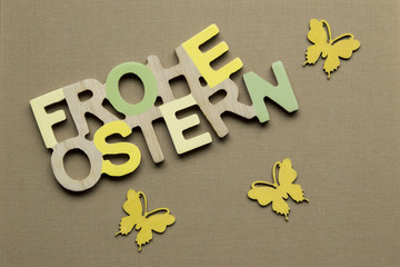 FROHE OSTERN Schrift in Naturfarben und 3 gelbe Schmetterlinge auf Hintergrund aus braunem Leinen