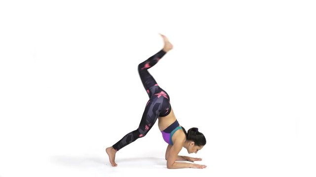 Young attractive woman practicing yoga doing Vrschikasana, Scorpion pose in full length, isolated over white studio background