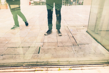 Low section of two people standing reflected on glass