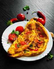 omelette in a plate on dark wooden background
