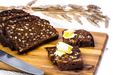 Rye bread with grains and butter on wooden kitchen board