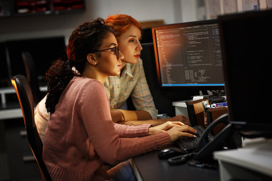 Two female programmers working on new project.They working late at night at the office.