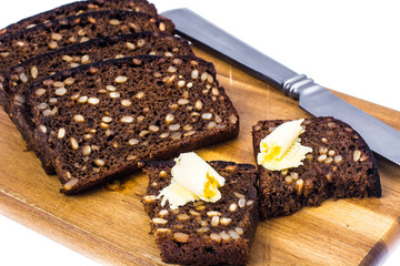 Rye bread with grains and butter on wooden kitchen board