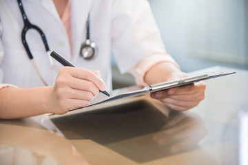 female doctor is writing something on clipboard.