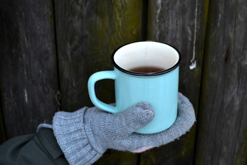 A mug of tea in cold weather. A cup of tea in woman's hands. 