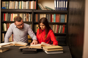 a guy with a girl getting ready for the exam read books in the library