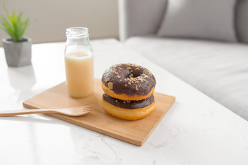 Chocolate donut. Morning breakfast with milk on table in living room at home.