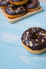 Chocolate glazed donuts on wooden background with blank space