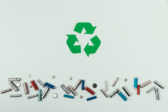 top view of recycle sign and various types of batteries isolated on grey