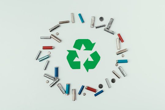 top view of recycle sign and various types of batteries in circle isolated on grey