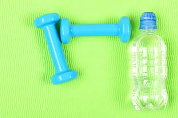 Pair of blue fitness dumbbells and bottle of water.